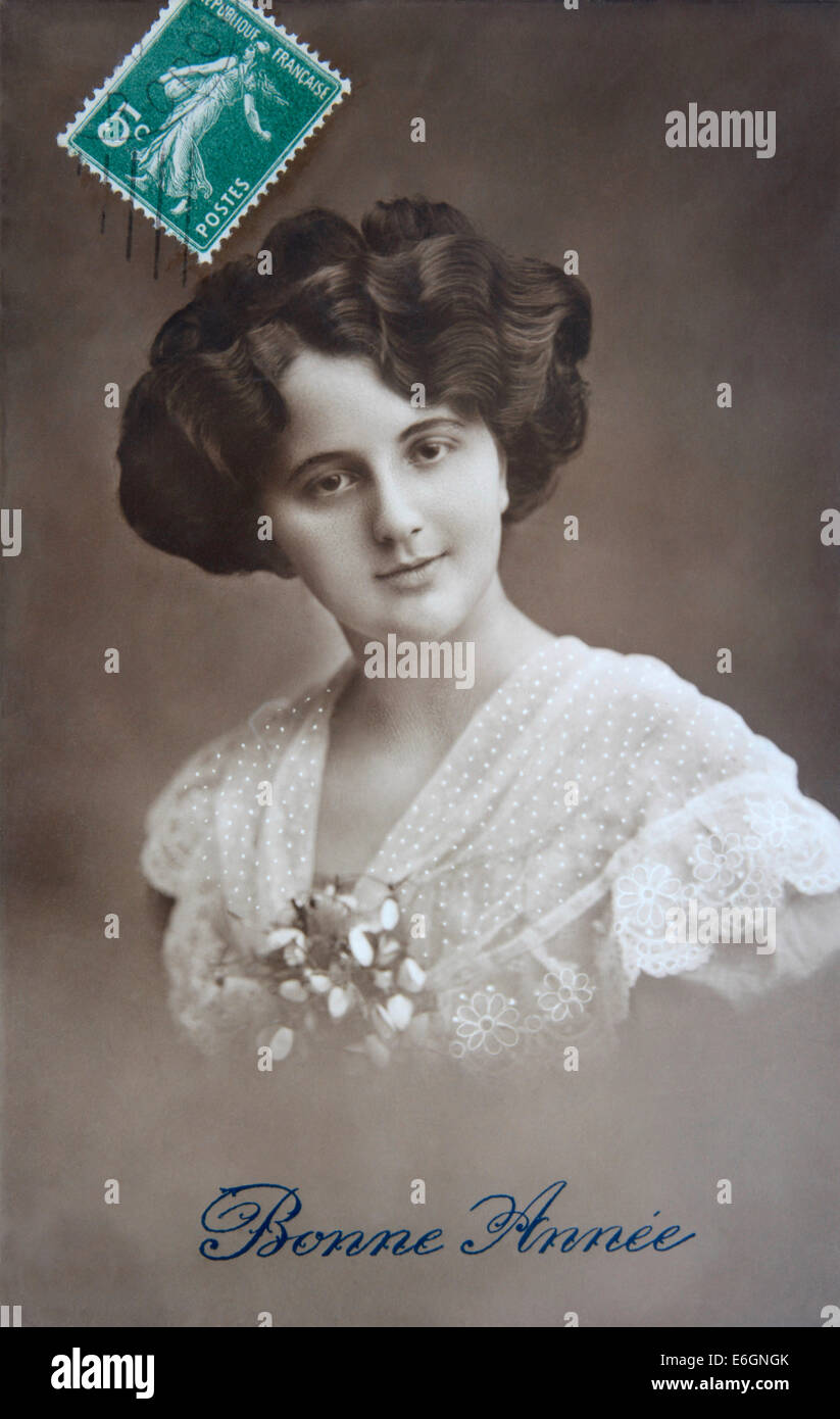 Cartolina d'epoca con una donna con capelli ricci e fiori, che celebra il nuovo anno nella Francia del XX secolo Foto Stock