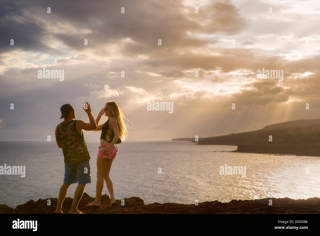 Giovane sulla scogliera dando alta cinque affacciato sulla baia di Lanai, Hawaii Foto Stock