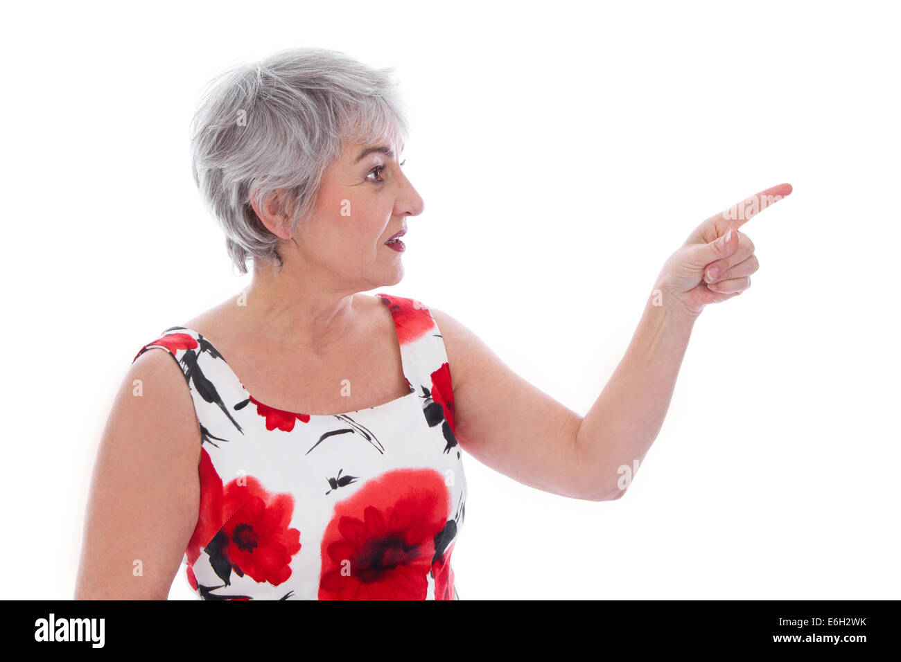 Attraente donna anziana isolato su bianco e indossando un vestito estivo puntando con il dito. Foto Stock