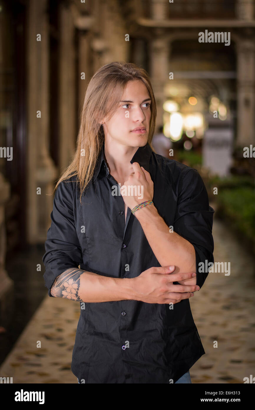 Bello capelli lunghi uomo ritratto in camicia nera in piedi in galleria  elegante in città europea centro Foto stock - Alamy