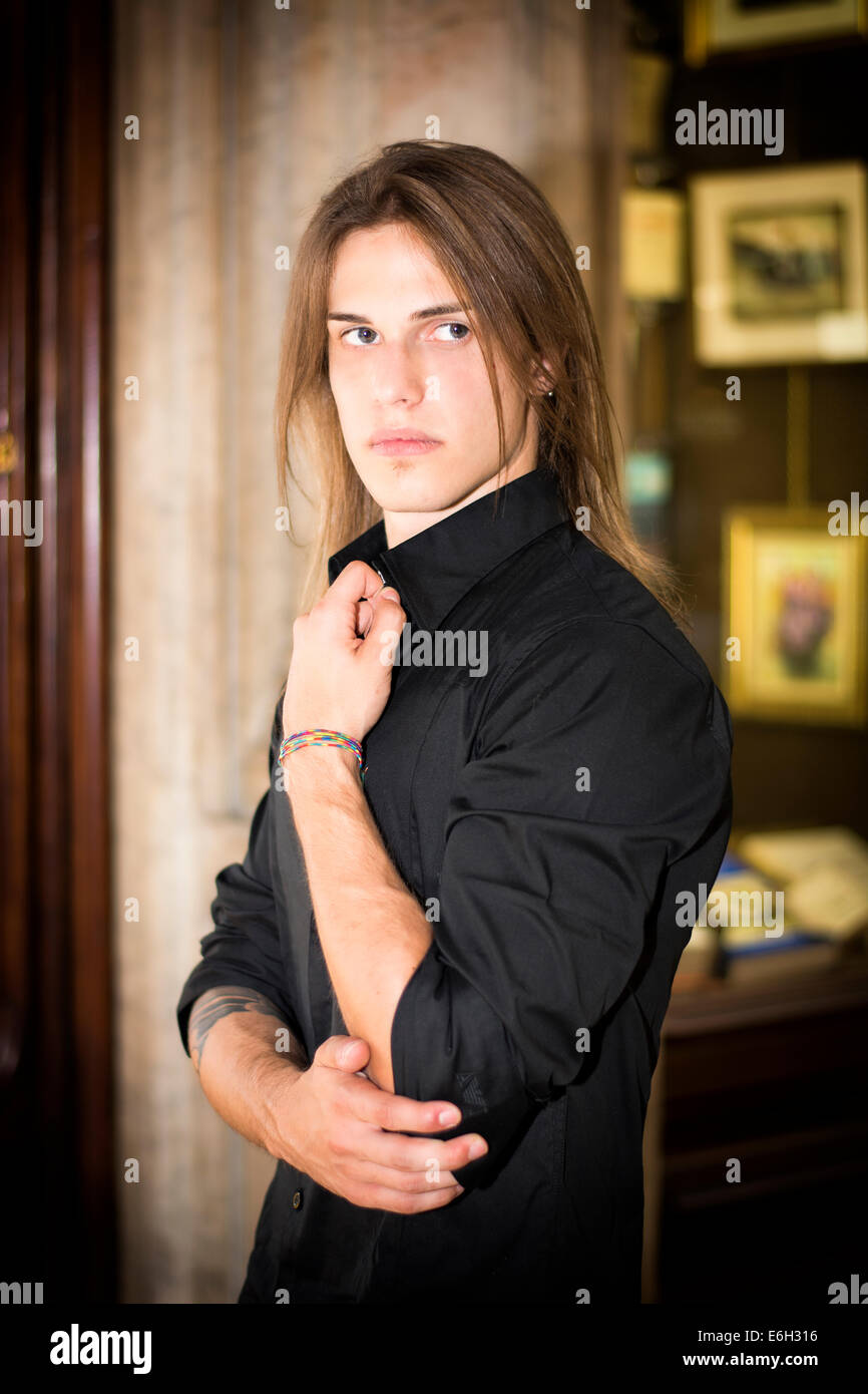 Bello capelli lunghi giovane uomo nella parte anteriore del negozio finestra indossando elegante camicia nera Foto Stock
