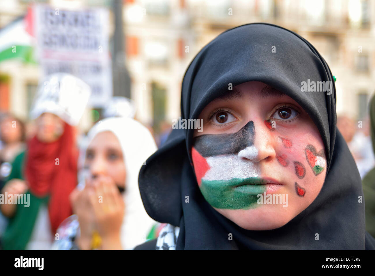 Giovane donna con una bandiera della Palestina dipinta sul suo viso per protestare contro gli attacchi israeliani nella Striscia di Gaza durante un demonstratio Foto Stock
