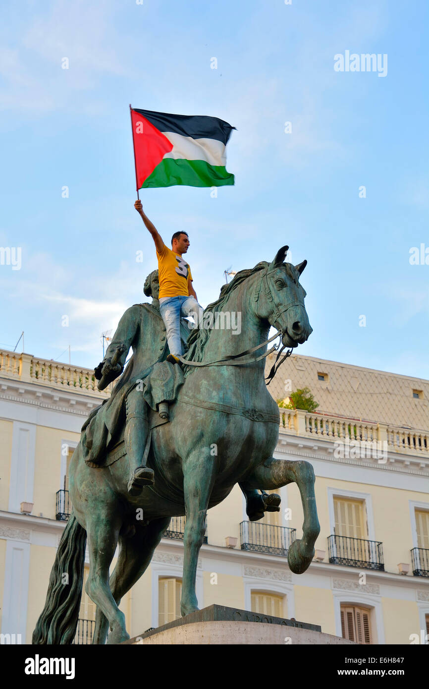 Un uomo si arrampica al 'Carlos III' statua e le onde di una Palestina bandiera durante una dimostrazione di sostenere i palestinesi a Madrid su J Foto Stock
