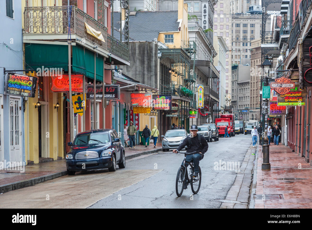 Giovane uomo Bicicletta Equitazione su un wet Bourbon Street nel Quartiere Francese di New Orleans Foto Stock
