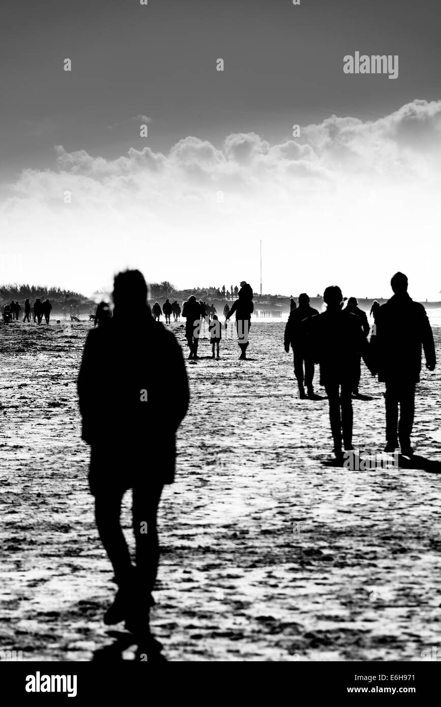 Sagome di persone facendo una passeggiata invernale sulla spiaggia Foto Stock