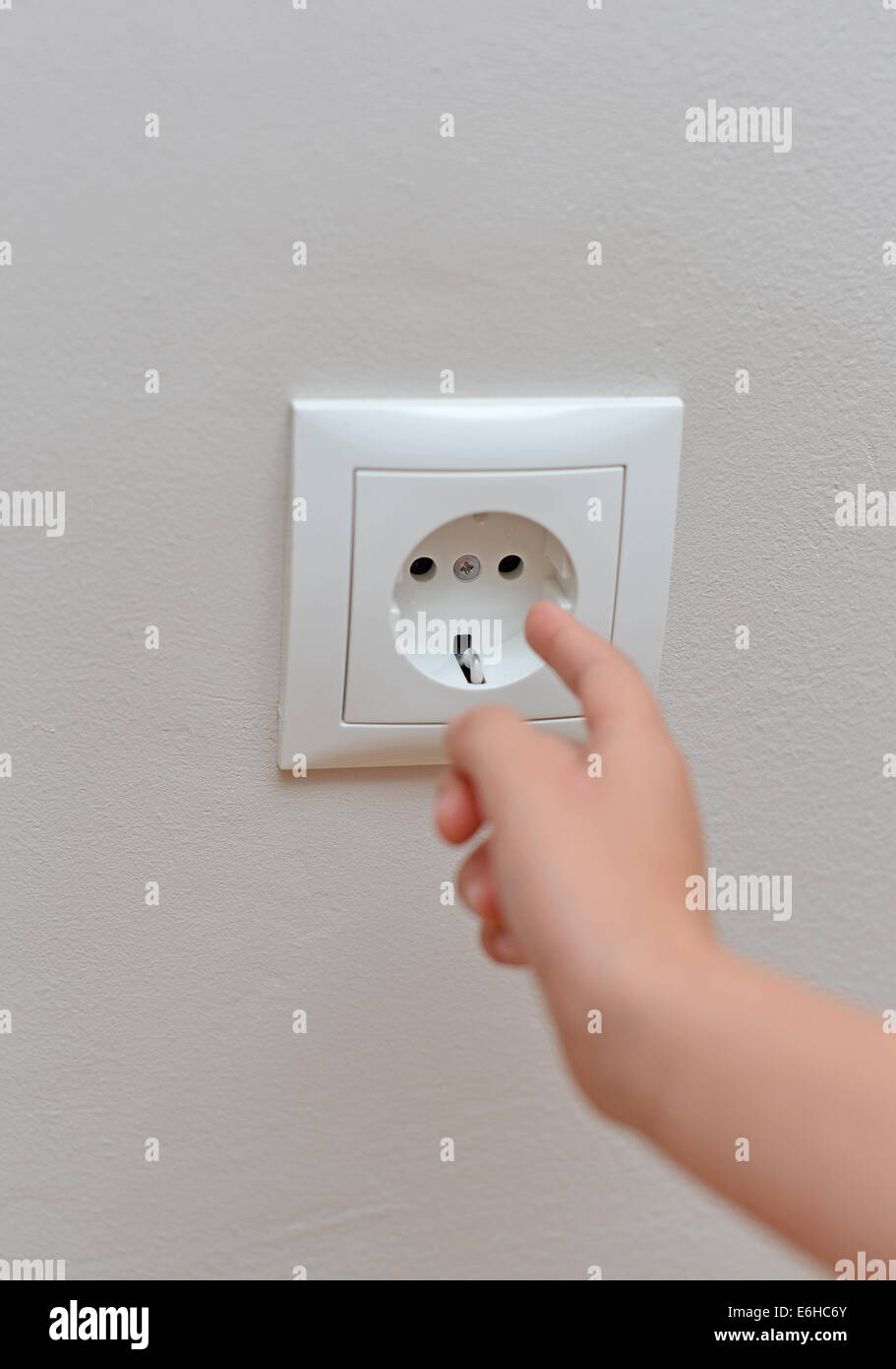 Bambino bastoni le sue dita nella presa. Situazione di pericolo a casa. Foto Stock