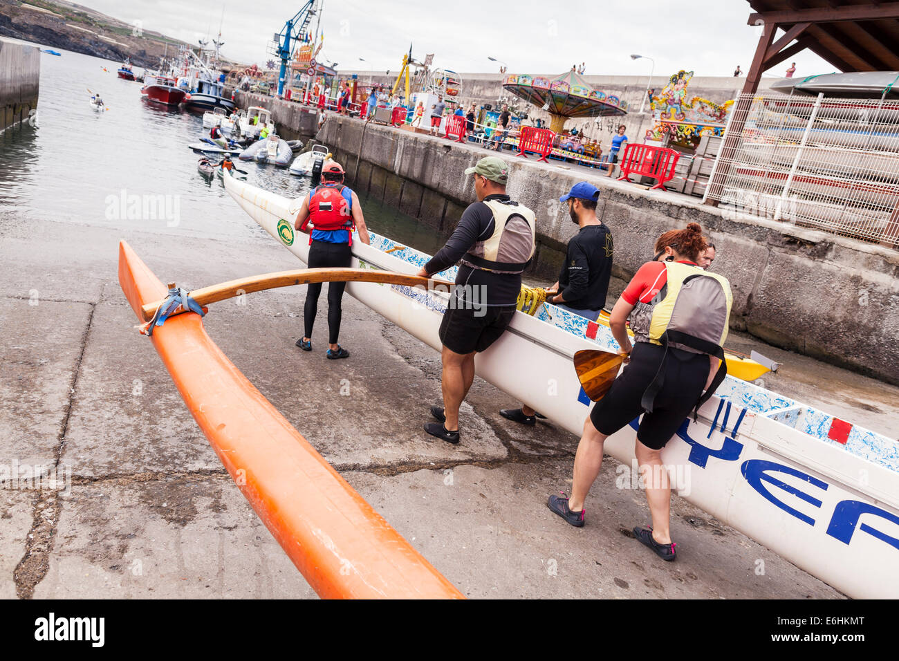 Sei uomo squadra di canottaggio lanciando una canoa outrigger at Playa San Juan, Tenerife, Isole Canarie, Spagna. Foto Stock