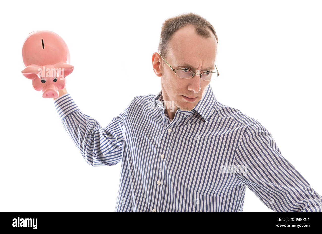 Furious isolato uomo calvo smashing il suo salvadanaio. Risparmio e finanza concetto. Foto Stock