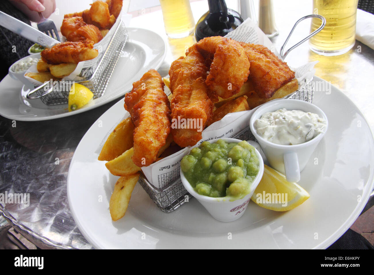 Posh Fish 'n' chips servita in un cestello con fiacco piselli, in un ristorante a Eyemouth, Berwickshire, Scozia Foto Stock