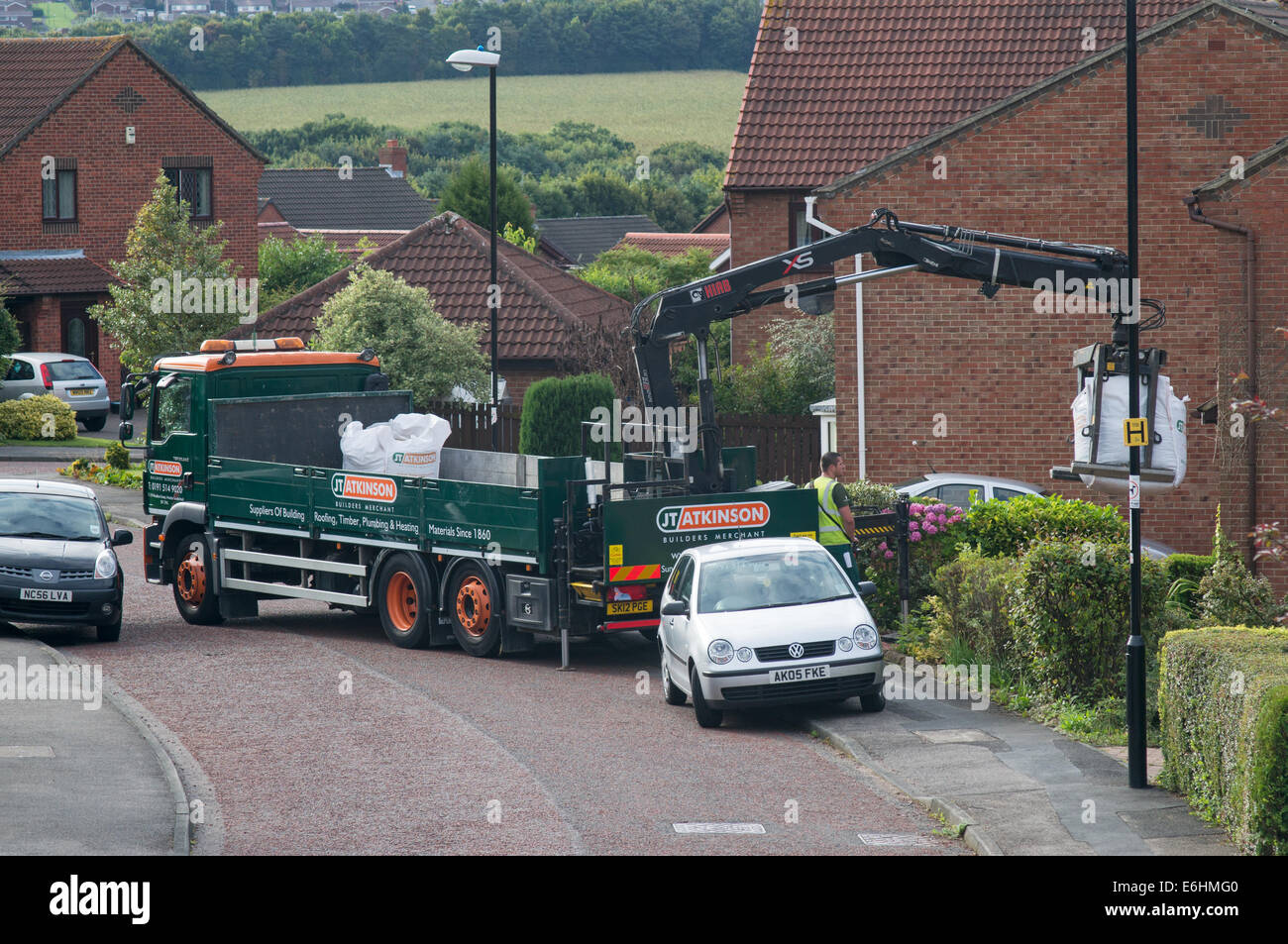 J T Atkinson builder merchant carrello con HIAB XS tailift gru offre a casa in suburban street , North East England Regno Unito Foto Stock