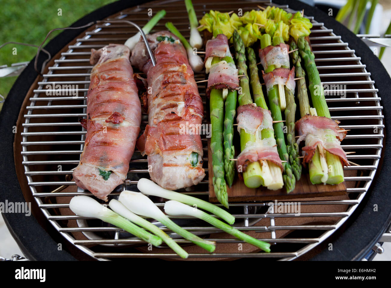 Filetto alla griglia di carne di maiale con ripieno di formaggio e spinaci rivestita con pancetta. Piatto di lato grigliate di giovani cipolla, gli asparagi e le zucchine. Foto Stock