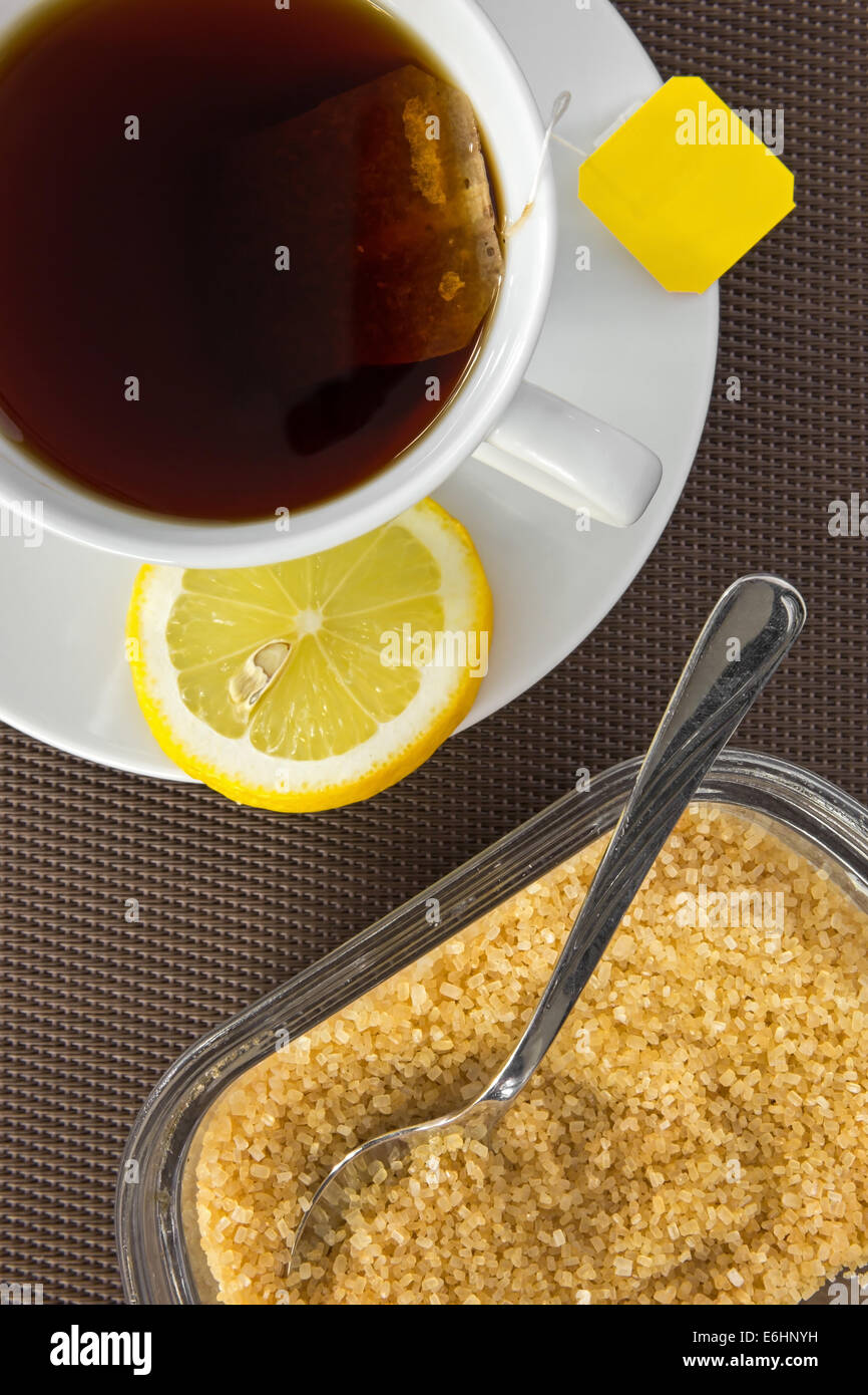 Vista aerea della tazza da tè, lo zucchero di canna e la fetta di limone Foto Stock