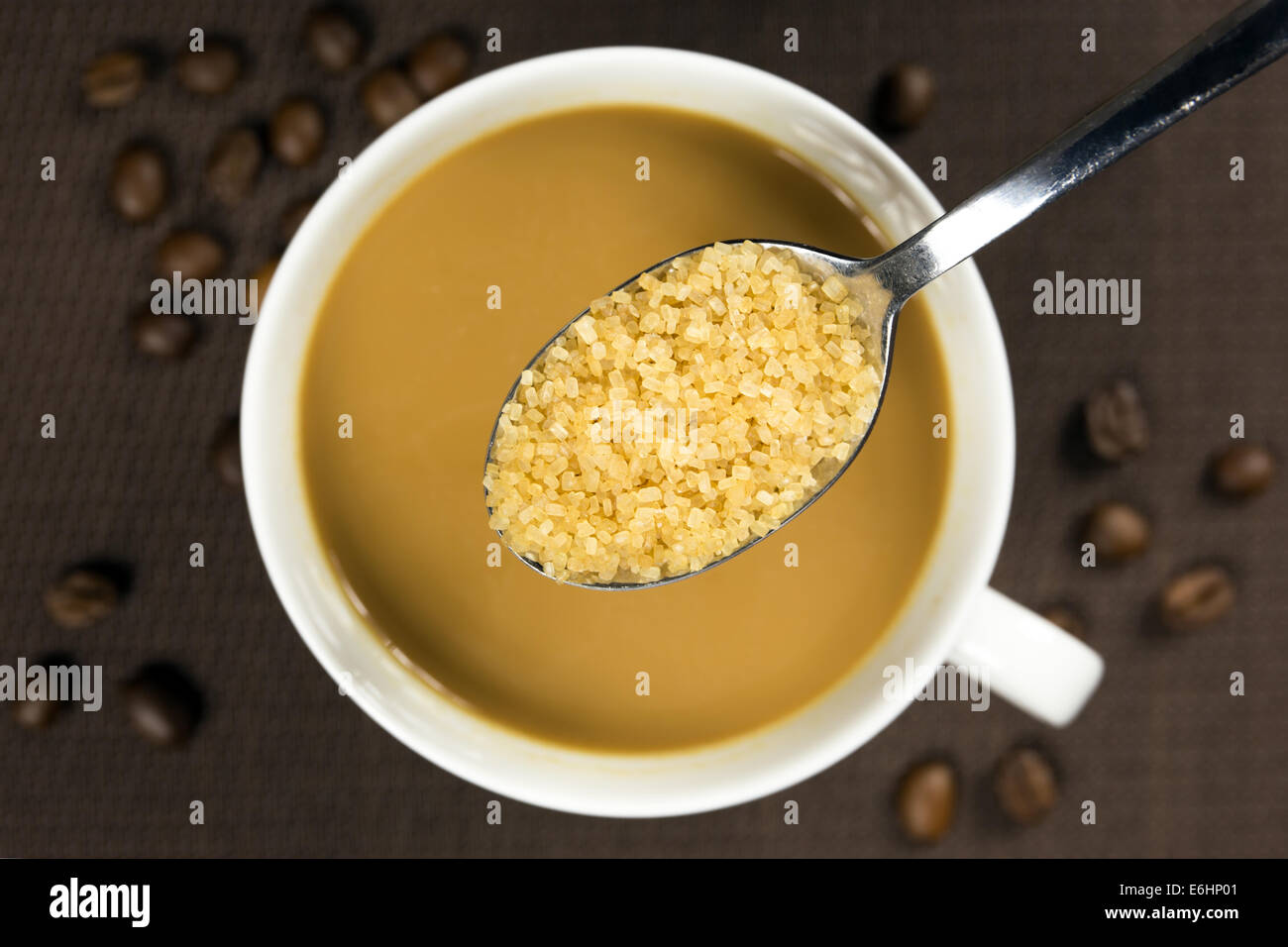 Lo zucchero di canna su un cucchiaio e una tazza di caffè al di sotto Foto Stock
