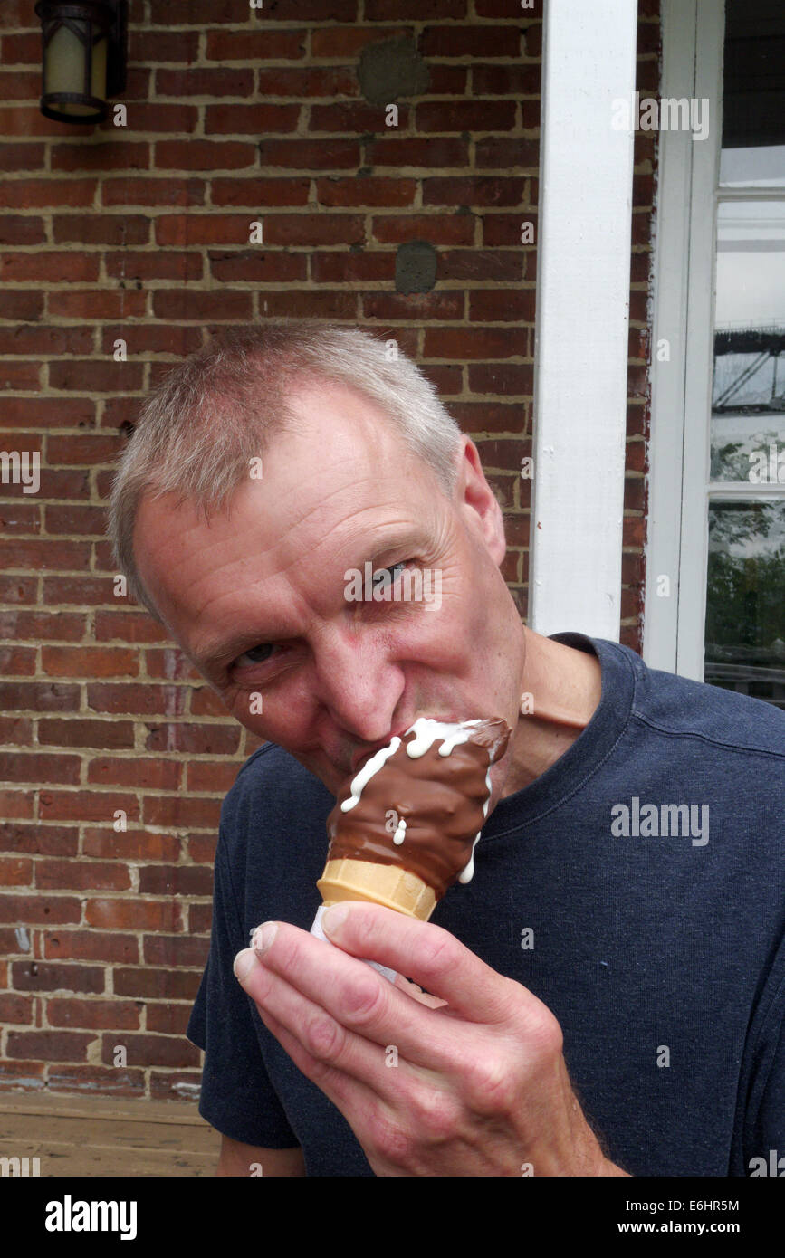 Un uomo di mangiare un gelato con un espressione ostile Foto Stock
