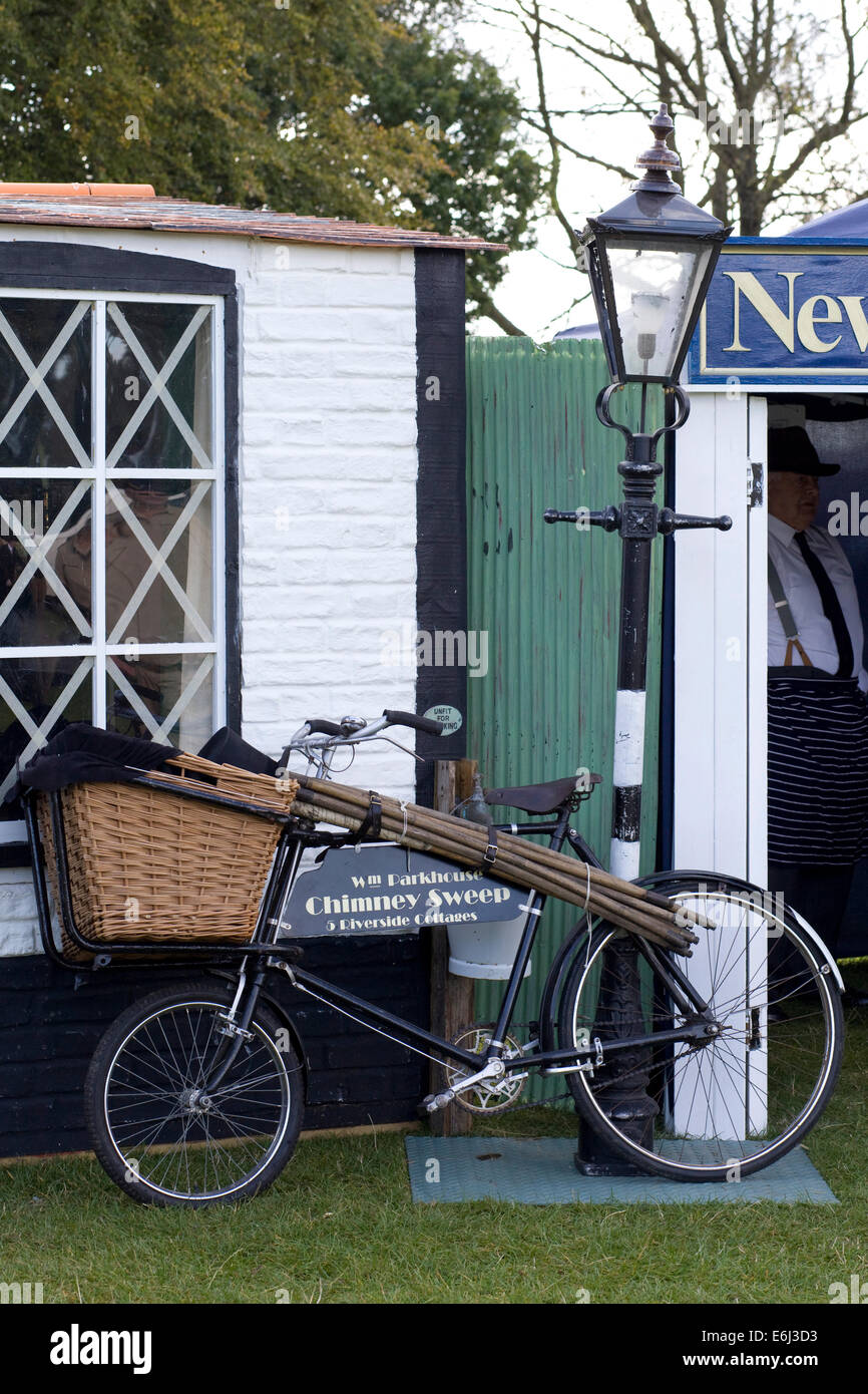 Replica 1940s tempo di guerra English shop con uno spazzacamino bicicletta appoggiata contro un lampione Foto Stock