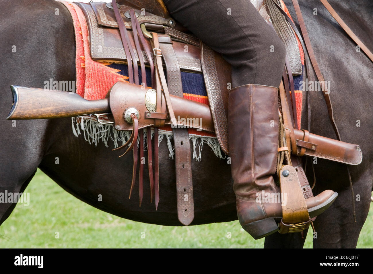 Seduta di cowboy a cavallo di un cavallo in una sella western con la sua riffle attaccata Foto Stock