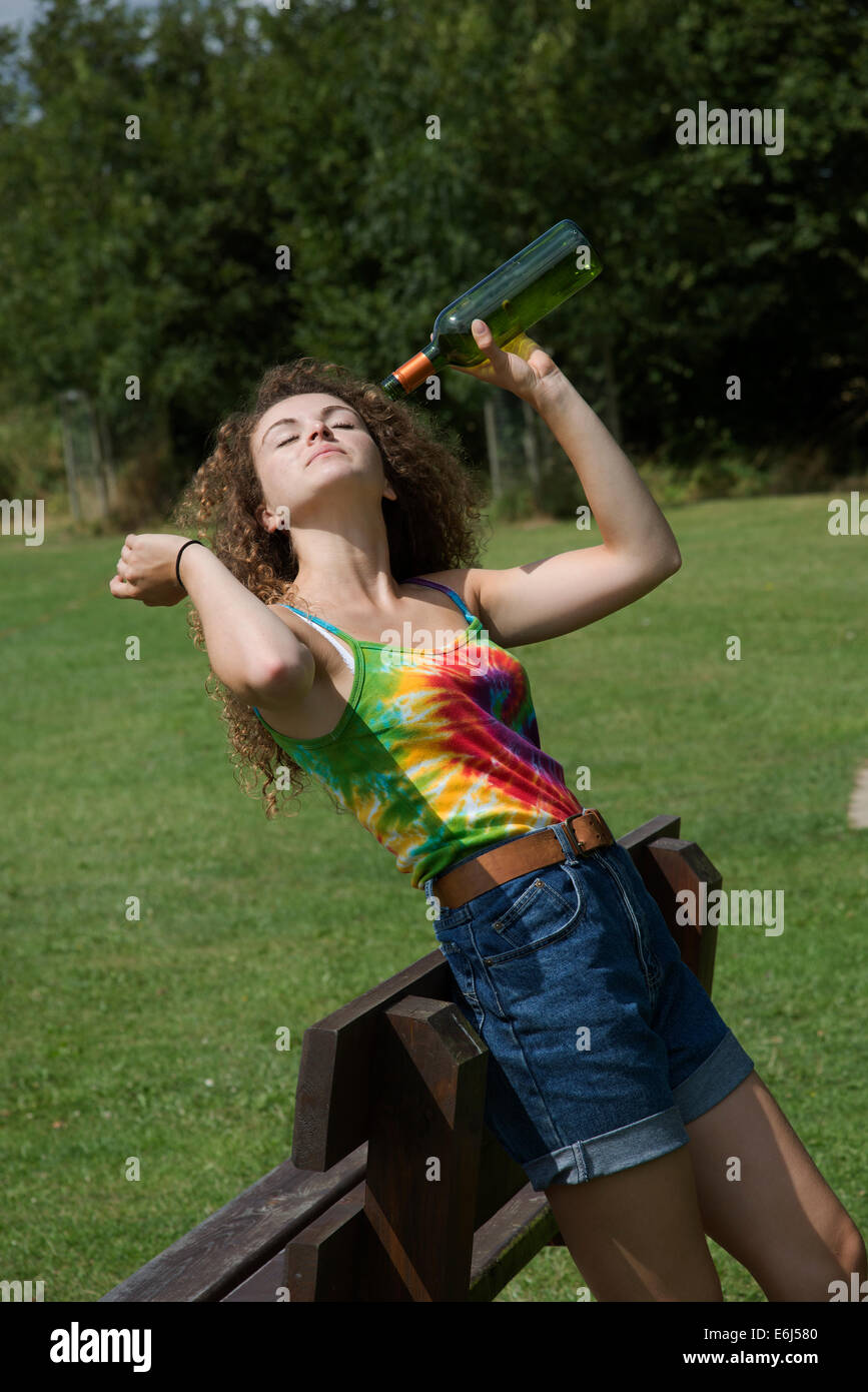 Ragazza adolescente di bere alcol su una panchina nel parco Foto Stock
