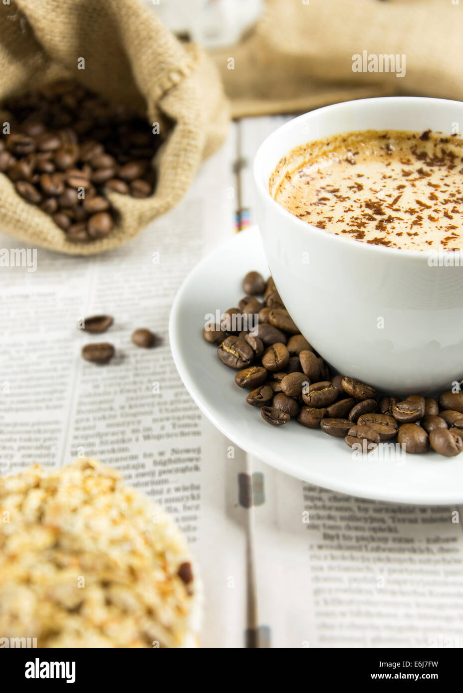 Tazza di caffè torrefatto in grani e un muffin disposti su un giornale Foto Stock