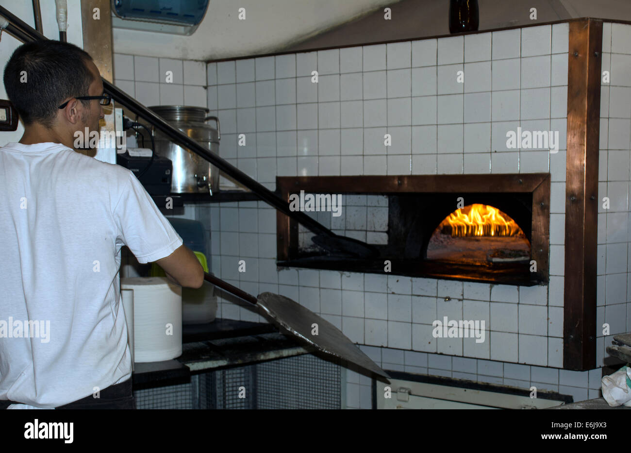 Un cuoco cuocere la pizza in forno a legna. Foto Stock
