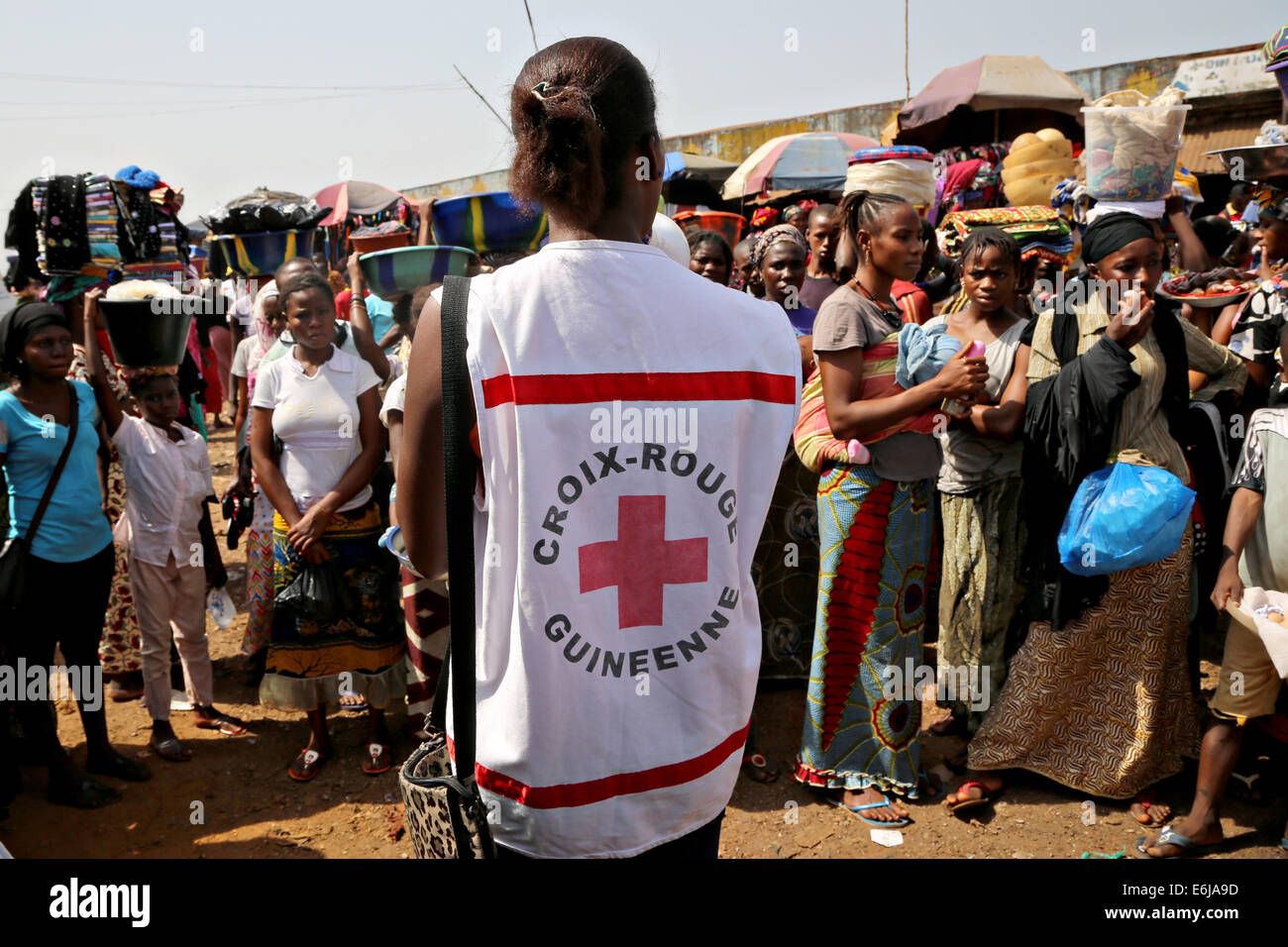 Volontari con la Società di Croce Rossa della Guinea istruire gli acquirenti sulle minacce da virus Ebola al mercato Matoto Aprile 1, 2014 a Conakry, in Guinea. Foto Stock