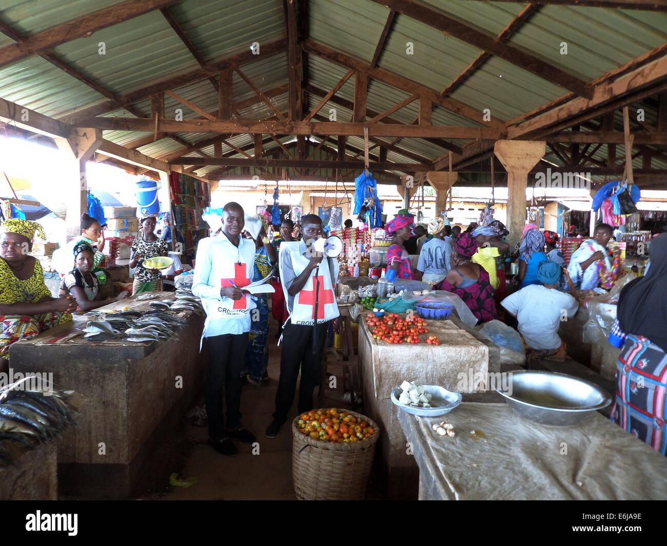 Volontari con la Società di Croce Rossa della Guinea istruire gli acquirenti sulle minacce da virus Ebola al mercato Matoto Aprile 1, 2014 a Conakry, in Guinea. Foto Stock