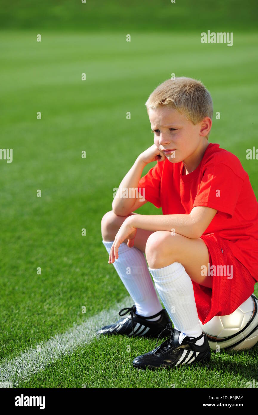 Ragazzo 9 10 11 giocando a calcio futbol soccer on Grassy passo campo non arrivare a giocare Foto Stock