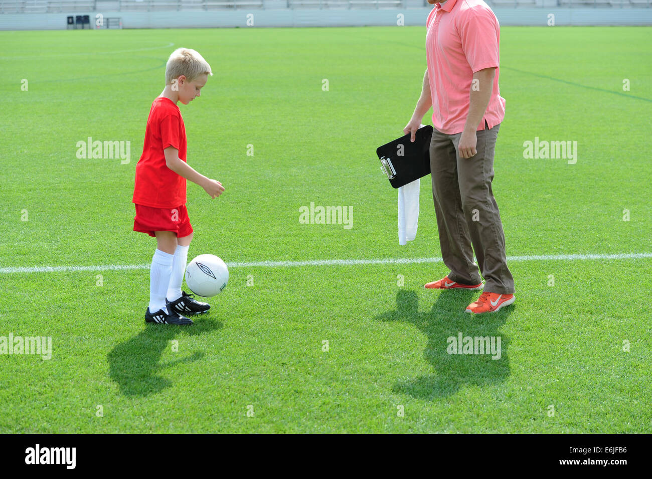 Ragazzo 9 10 11 giocando a calcio futbol soccer on Grassy campo di passo in fase di riscaldamento con pulmann pratica Foto Stock