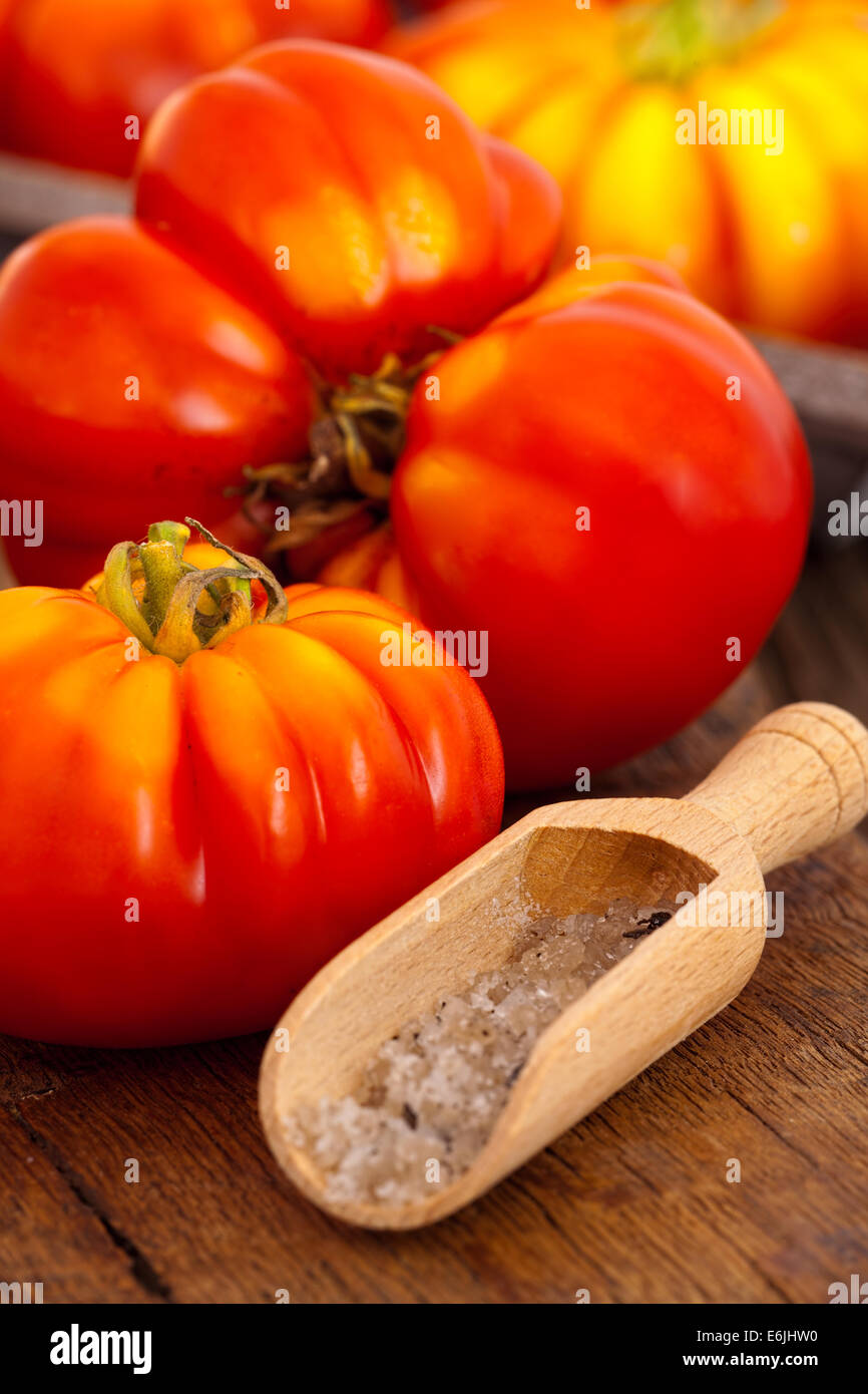 Carni bovine maturi i pomodori e il sale di spezie scoop su un vecchio rustico tagliere in stile country Foto Stock