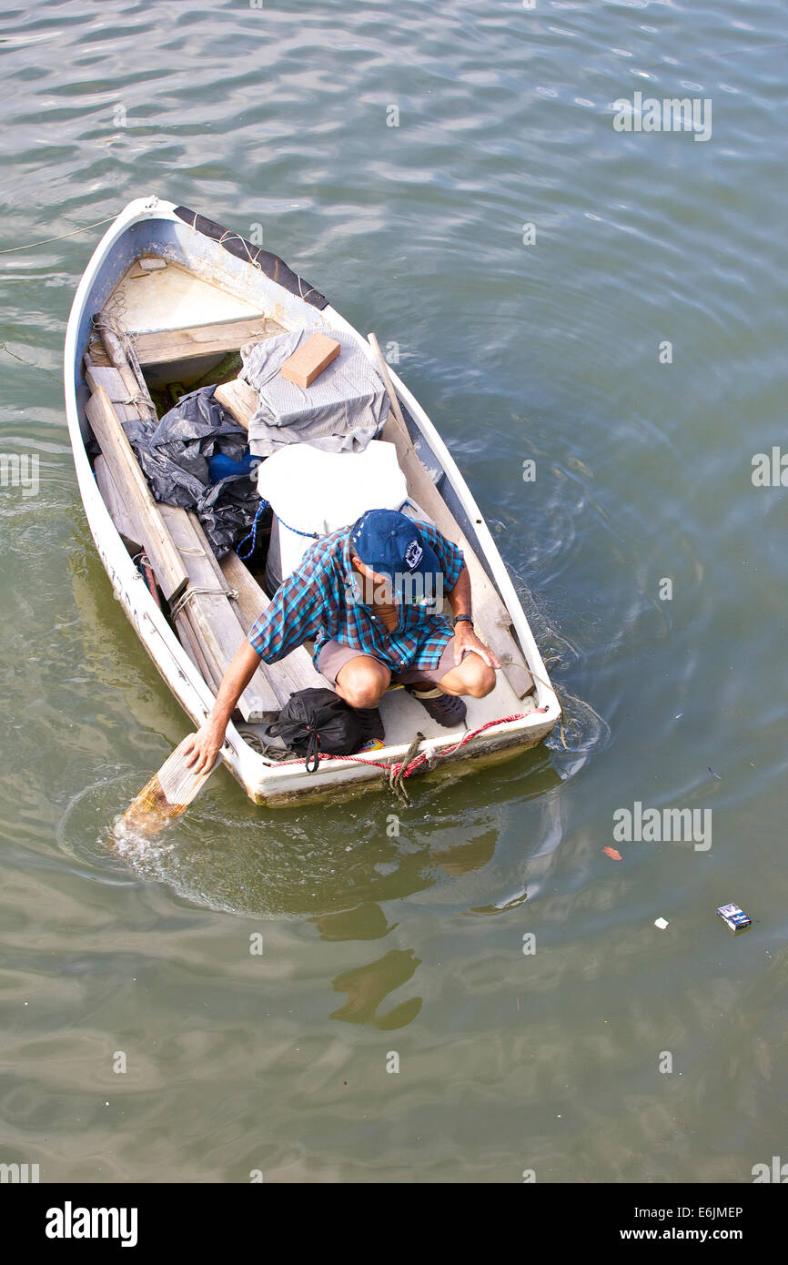 Il vecchio uomo cinese pagaie la sua barca verso la riva in Causeway Bay Typhoon Shelter, Hong Kong. Foto Stock