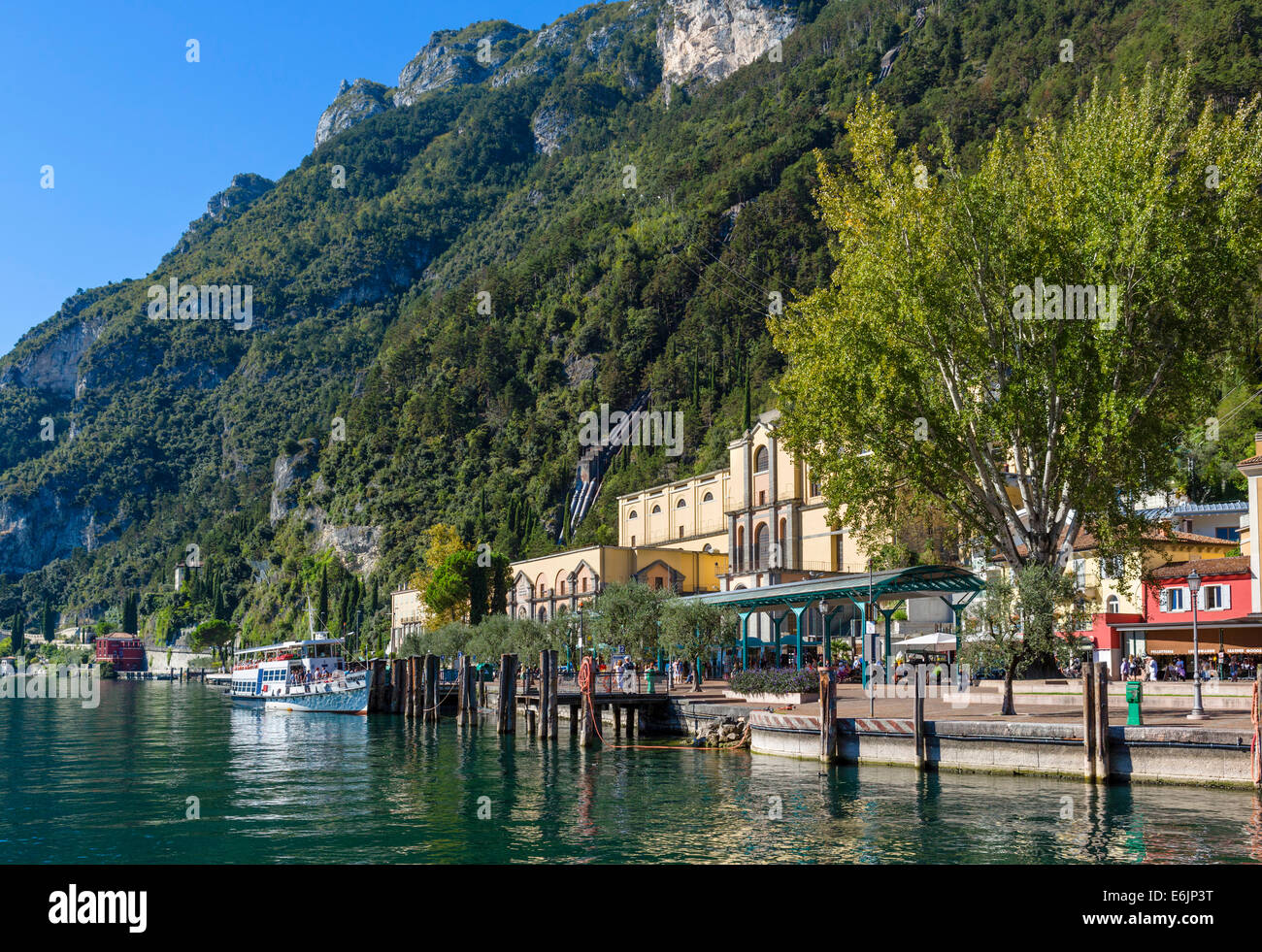 Il lungomare di Riva del Garda, con tubi su una collina dalla centrale idroelettrica sul Lago di Garda, Trentino Alto Adige, Italia Foto Stock