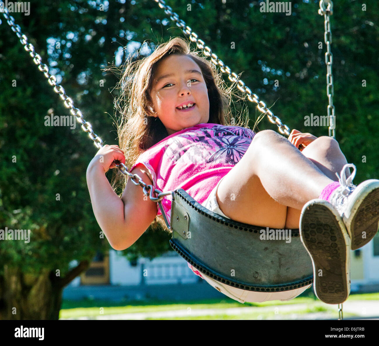 Estate fotografia di sette anno vecchia ragazza su un parco giochi swing Foto Stock