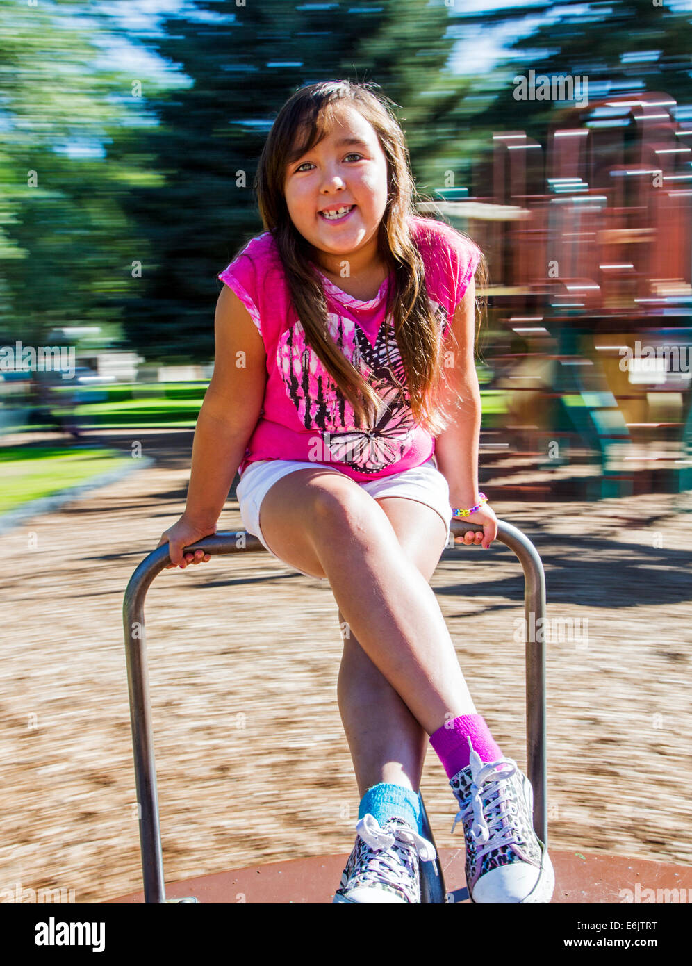Estate fotografia di sette anno vecchia ragazza su un parco giochi merry-go-round Foto Stock