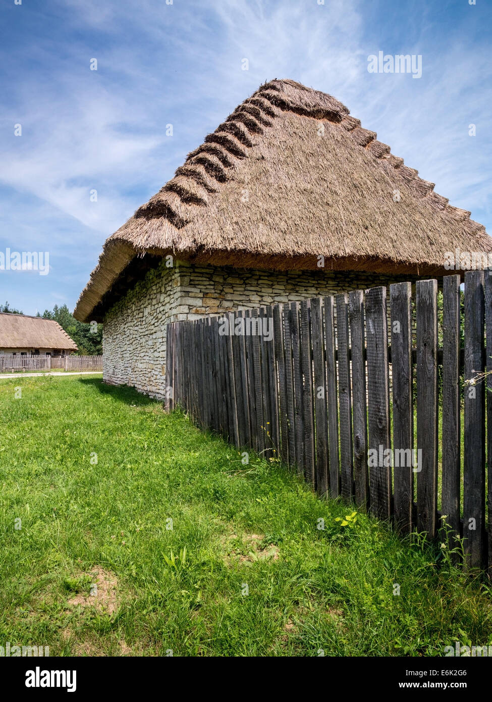 Cascina con cottage con tetto in paglia e Picket Fence shot contro il cielo blu Foto Stock