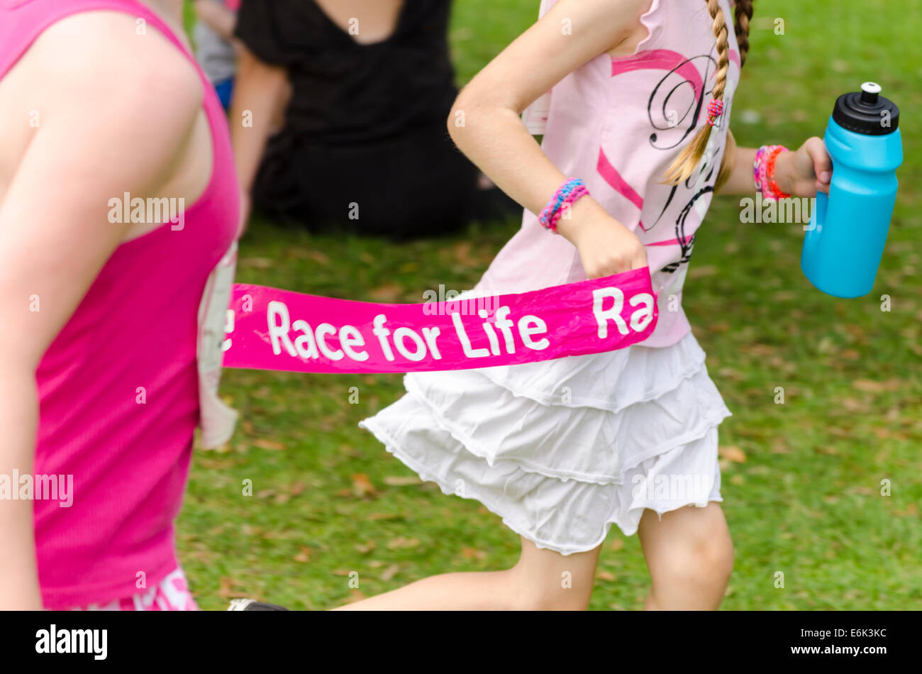 Due ragazze in esecuzione con un banner Race-per-evento di vita REGNO UNITO Foto Stock