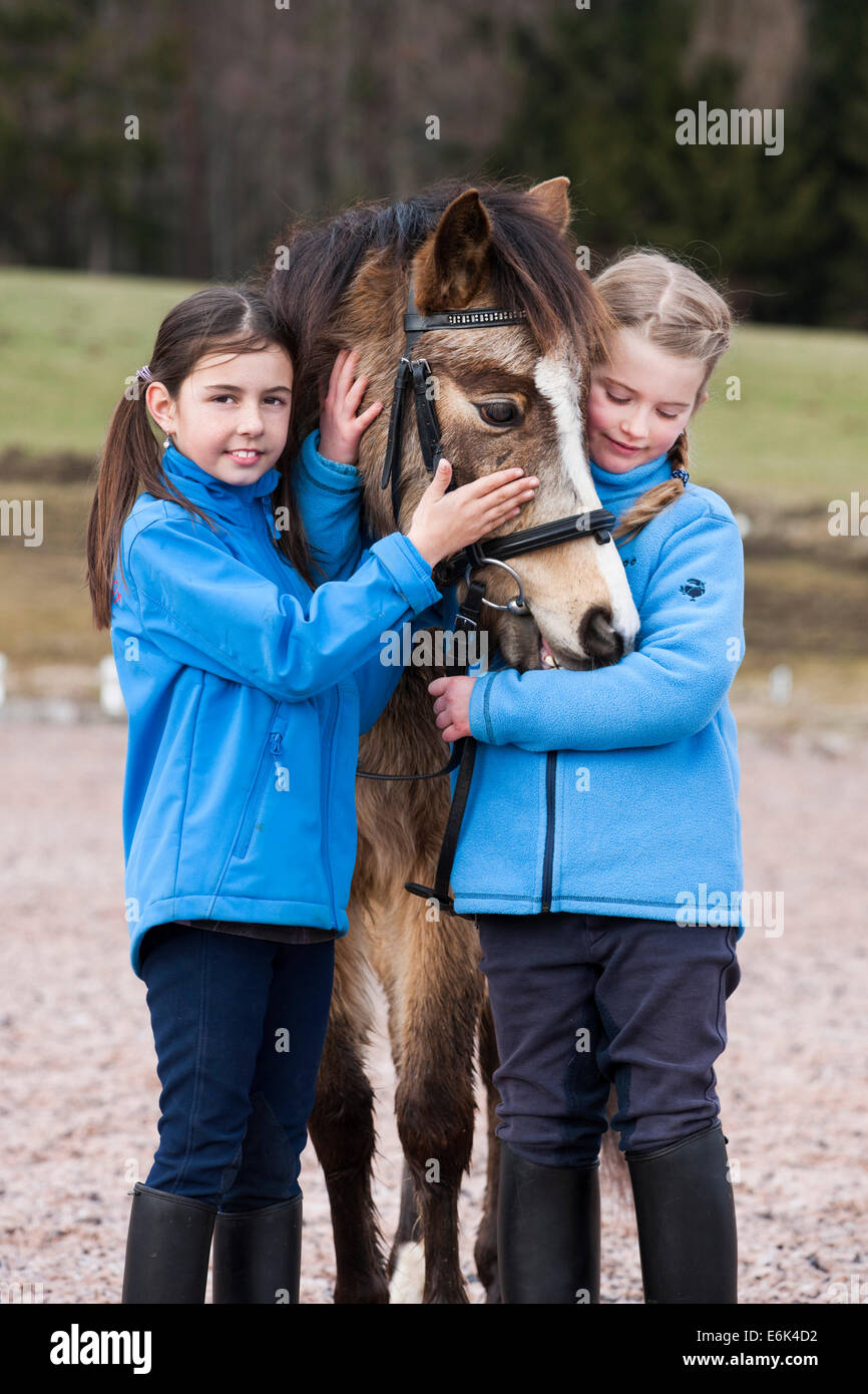 Due ragazze in piedi accanto a un pony, dun, con una briglia, Tirolo, Austria Foto Stock