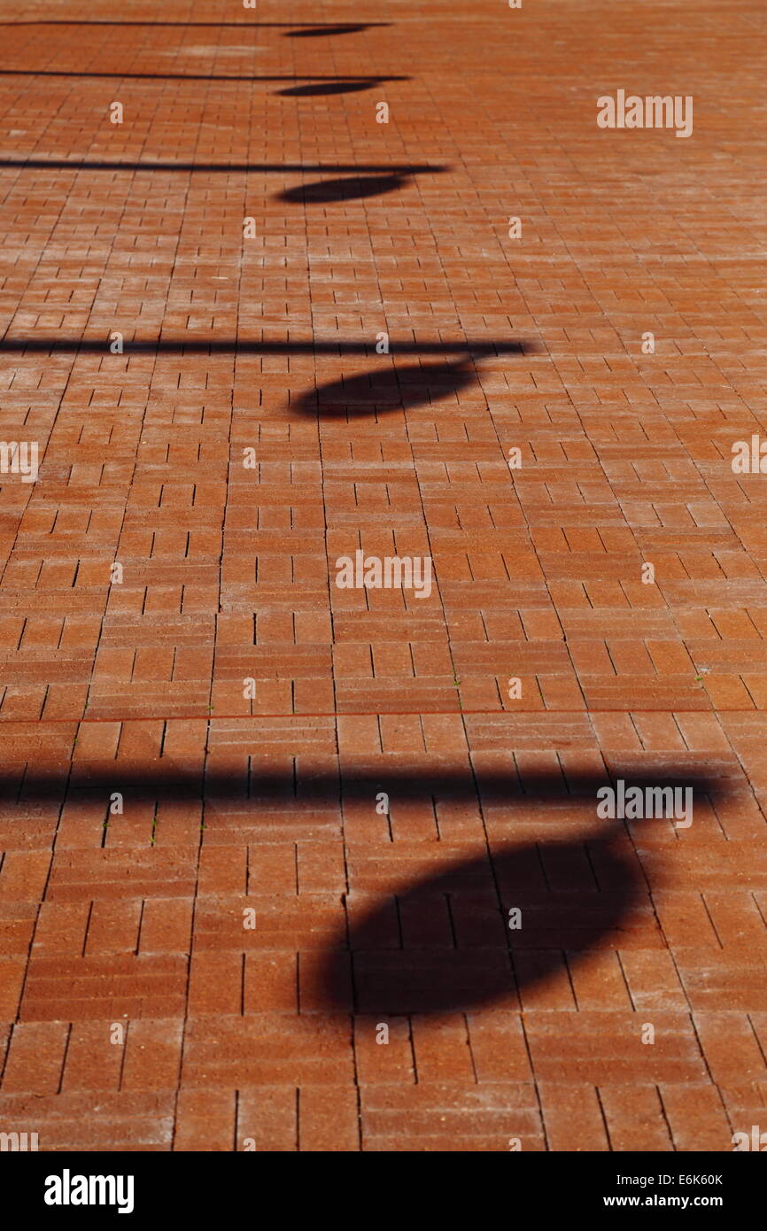 Le ombre in una fila su un cortile in mattoni. Guarda come musicale "trimestre note.' Perth, Western Australia. Foto Stock