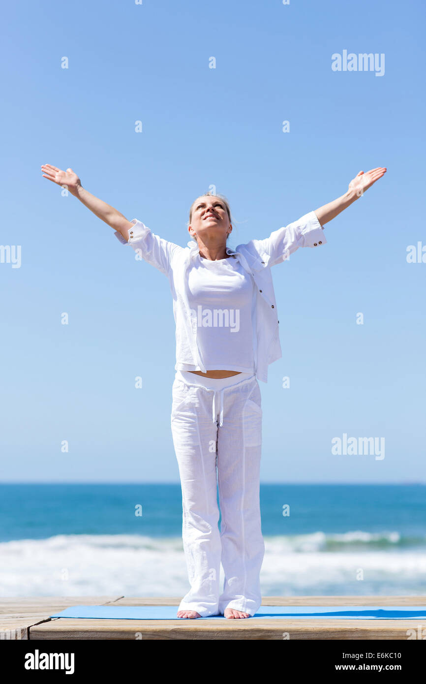 Un sano donna di mezza età armi raggiungono fuori sulla spiaggia Foto Stock