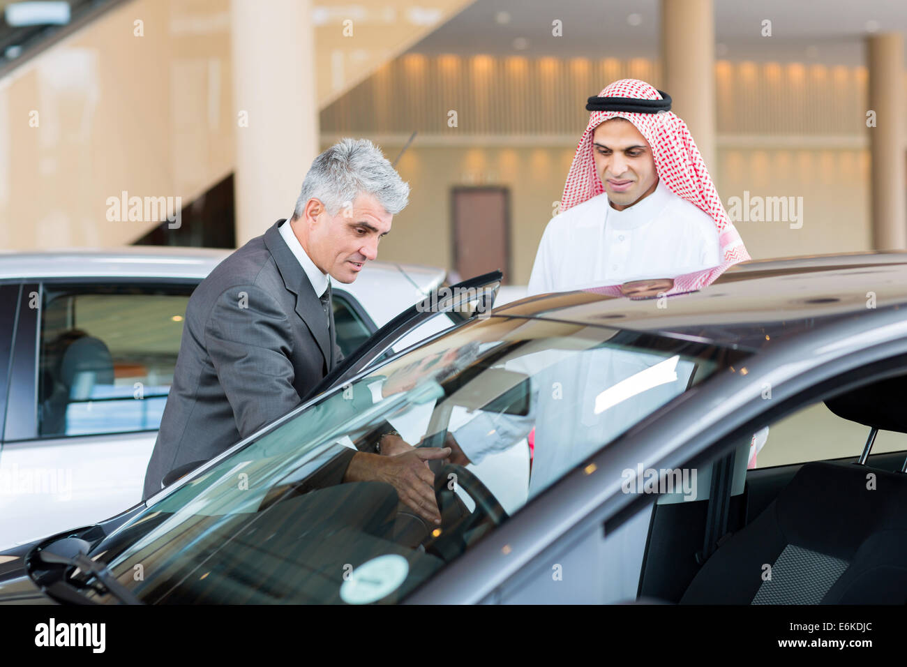 Persone di mezza età rivenditore di auto che mostra la nuova vettura per il potenziale acquirente arabo Foto Stock