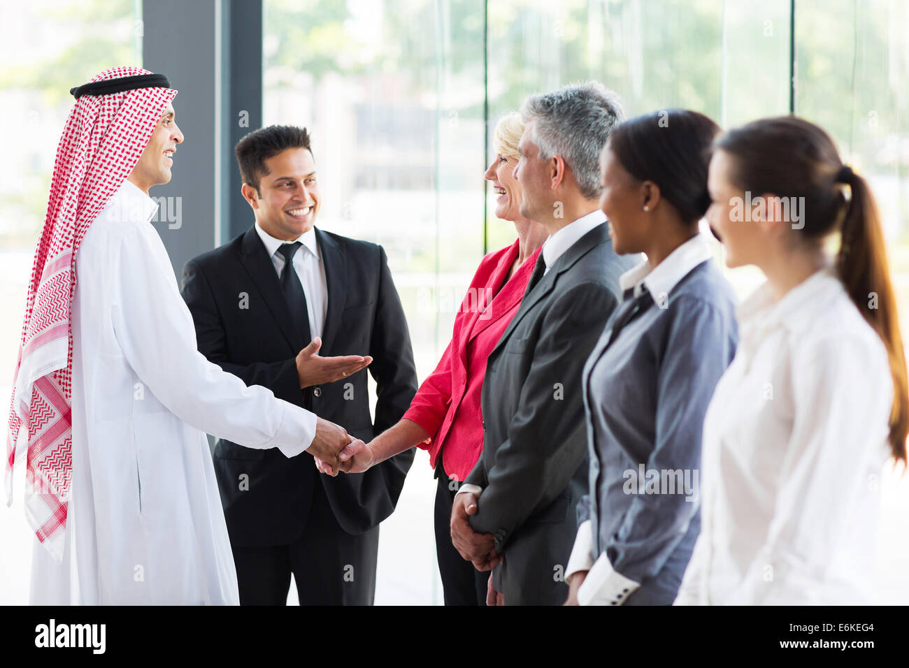 Traduttore giovani introducendo Arabian imprenditore a partner aziendali Foto Stock