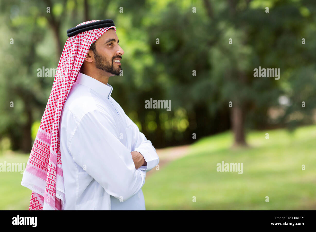 Carino Arabian uomo con le braccia incrociate che guarda lontano Foto Stock