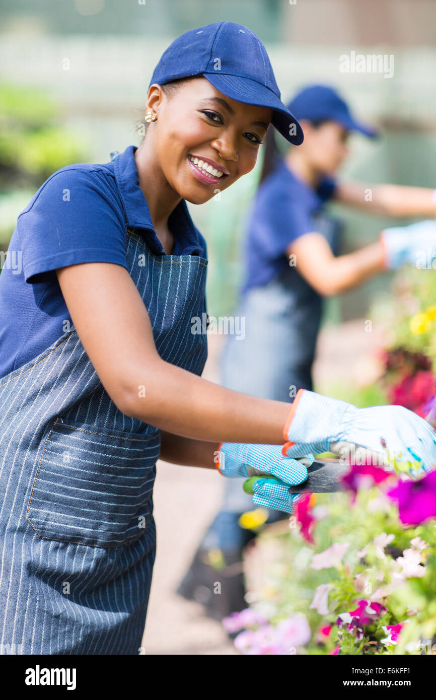 Bella americana africana fiorista femmina lavorando in vivaio Foto Stock