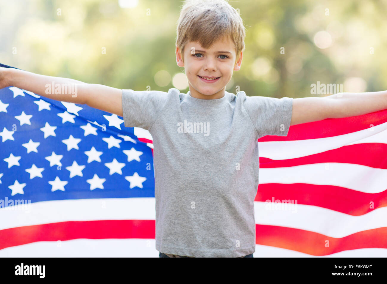 Ritratto di carino piccolo ragazzo holding bandiera americana all'aperto Foto Stock