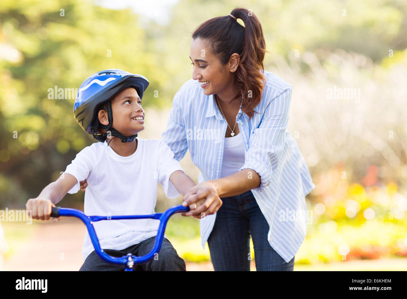 Madre amorevole aiuto di suo figlio carino andare in bicicletta Foto Stock