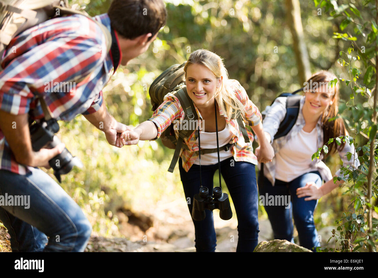 Giovane uomo aiutando gli amici a salire la roccia Foto Stock