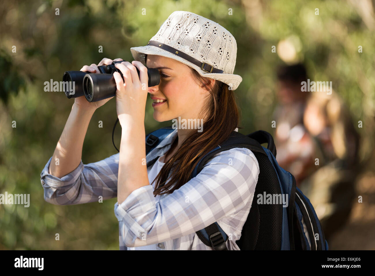 Allegro giovane donna con il binocolo bird watching nella foresta Foto Stock