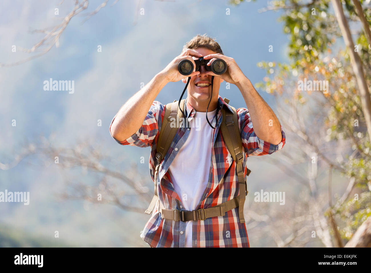 Giovane maschio escursionista usando il binocolo sulla cima della montagna Foto Stock