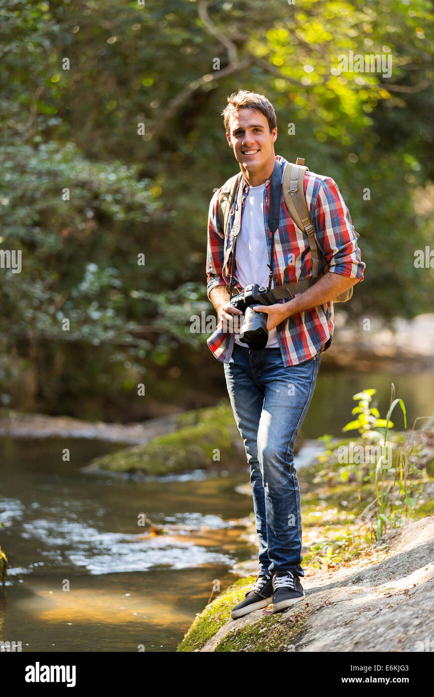 Giovane uomo con fotocamera DSLR in piedi alla valle di montagna Foto Stock