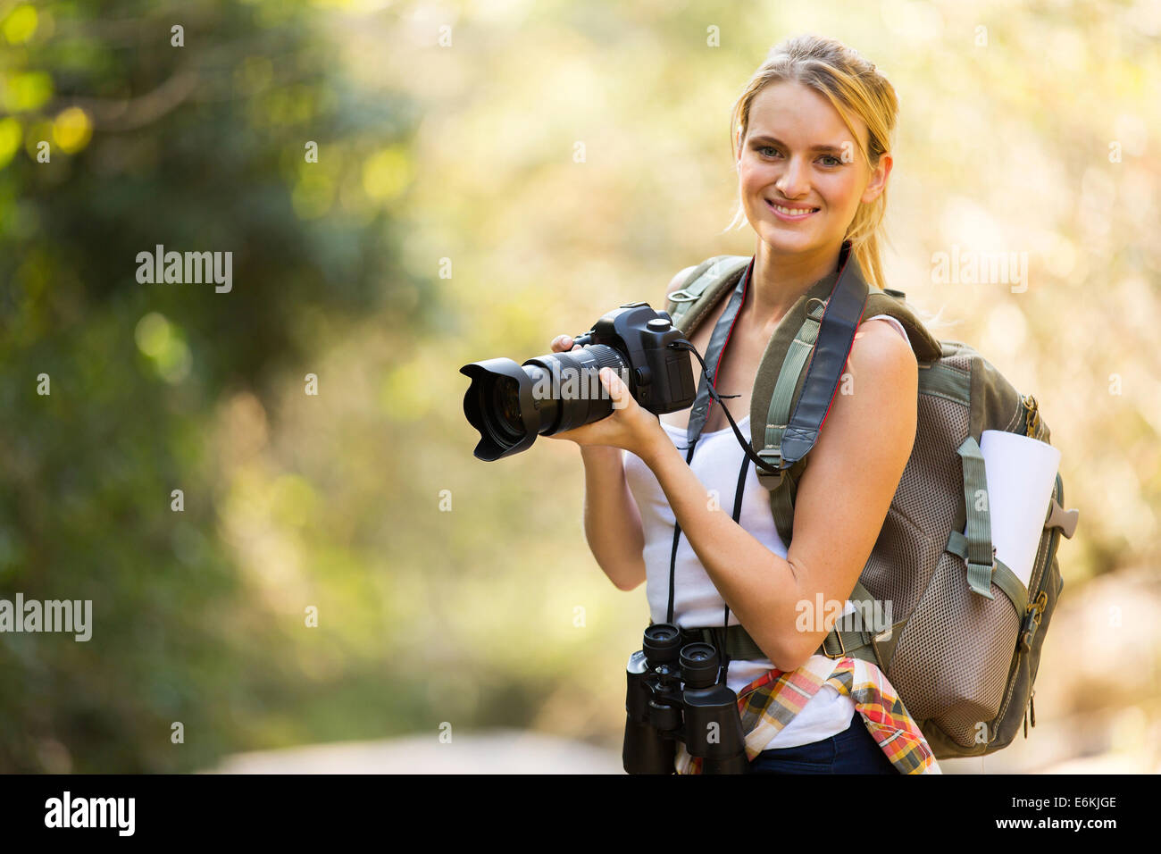 Giovane donna in possesso di una fotocamera reflex digitale in valle di montagna Foto Stock