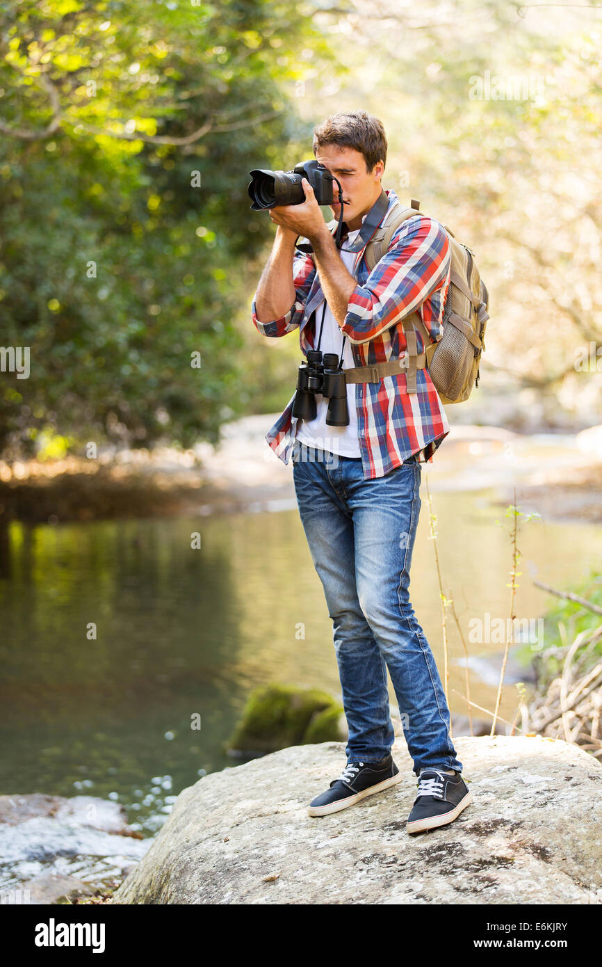 Giovane uomo Scattare foto nella valle di montagna con fotocamera reflex digitale Foto Stock