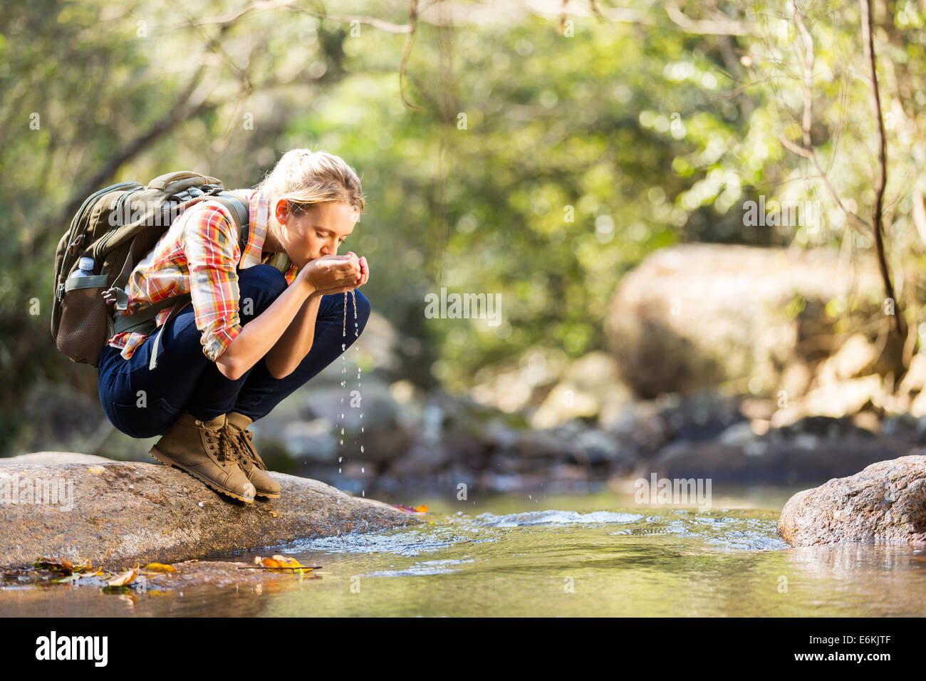 Giovane escursionista di bere acqua di ruscello in montagna Foto Stock